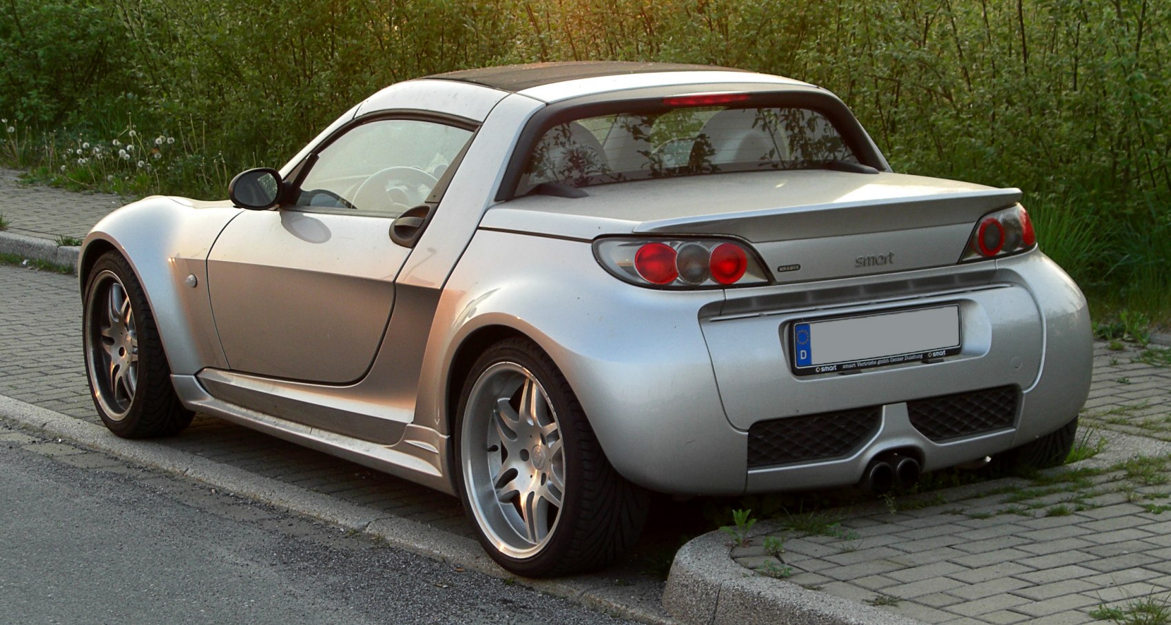 Rear view showing circular taillights and dual exhausts of a sporty roadster.