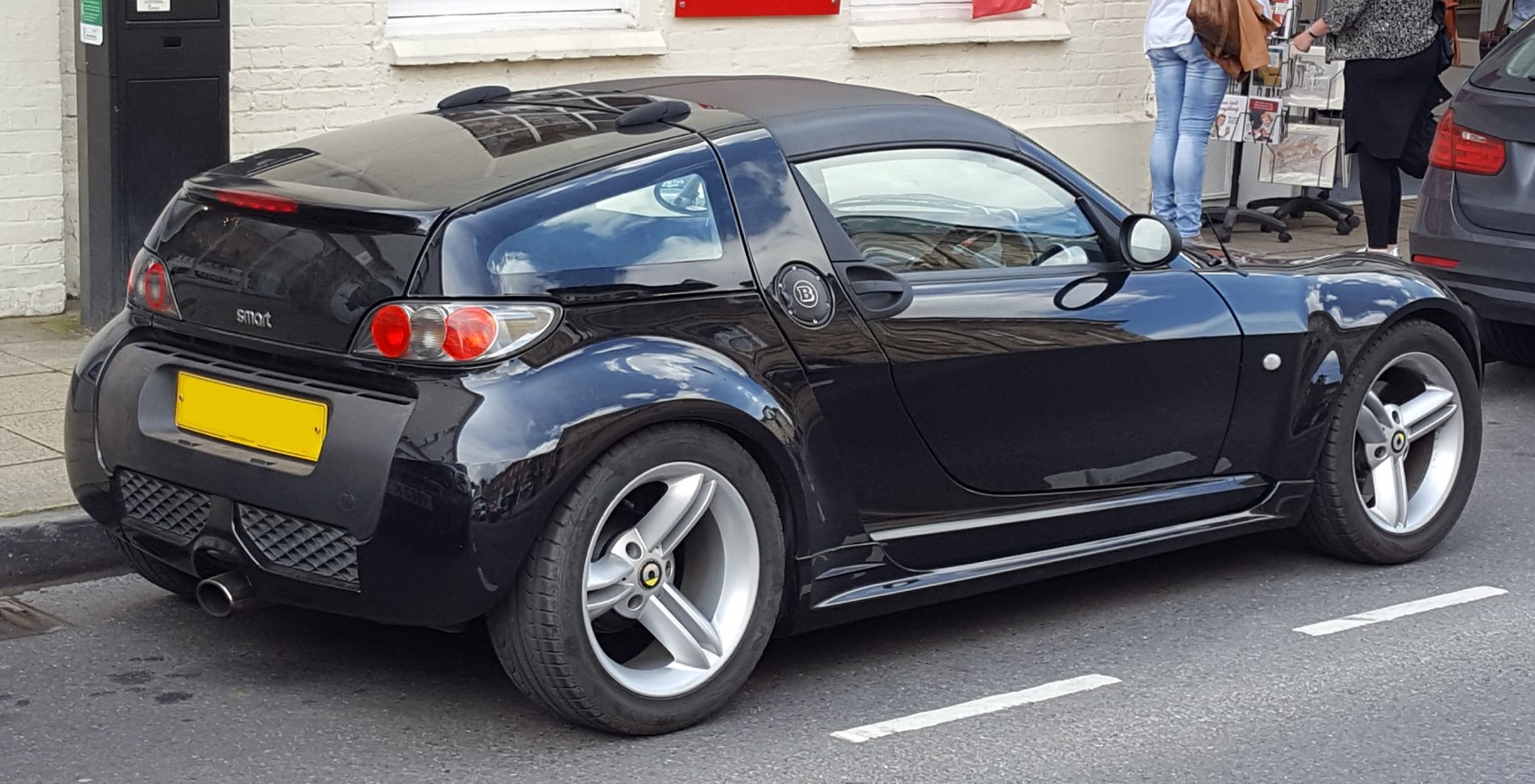 Rear side view of a small coupe with unique taillights and three-spoke alloy wheels