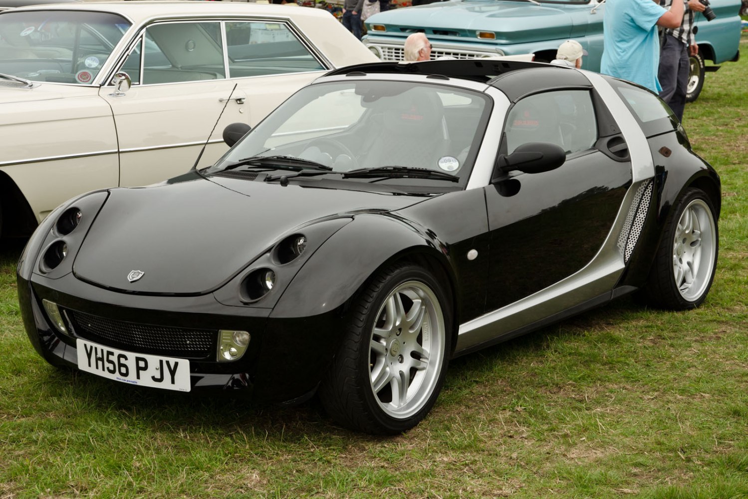 Black compact roadster with quad round headlights and silver trim