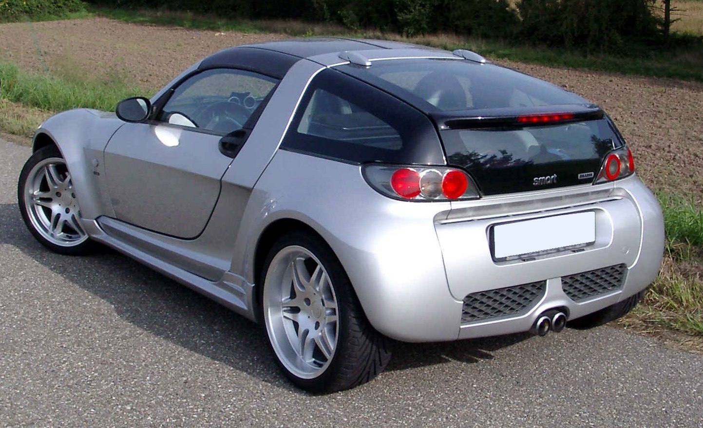Rear and side profile of a compact sporty coupe with dual exhaust and distinctive taillights