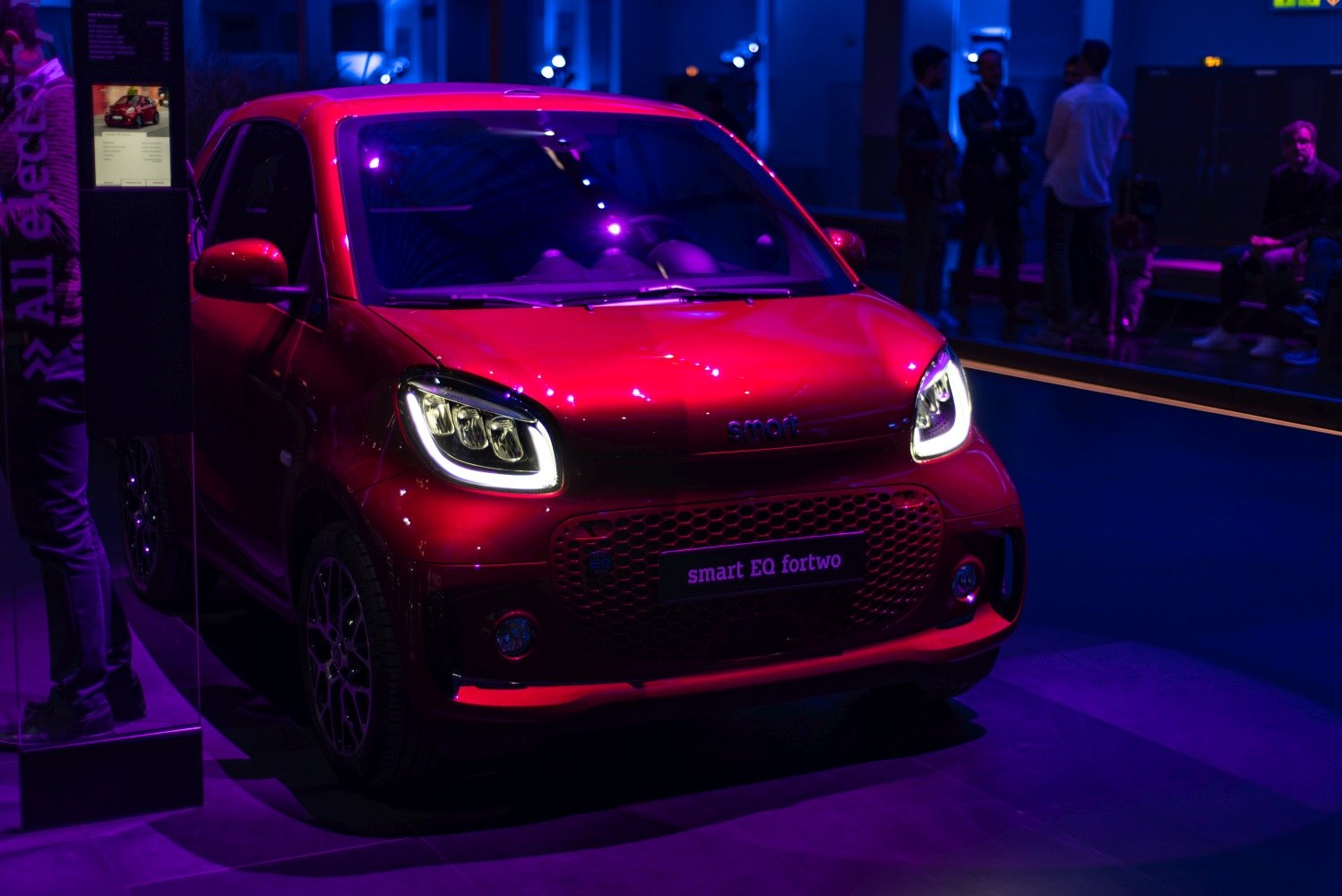 Front view with LED headlights of compact electric hatchback in showroom lighting