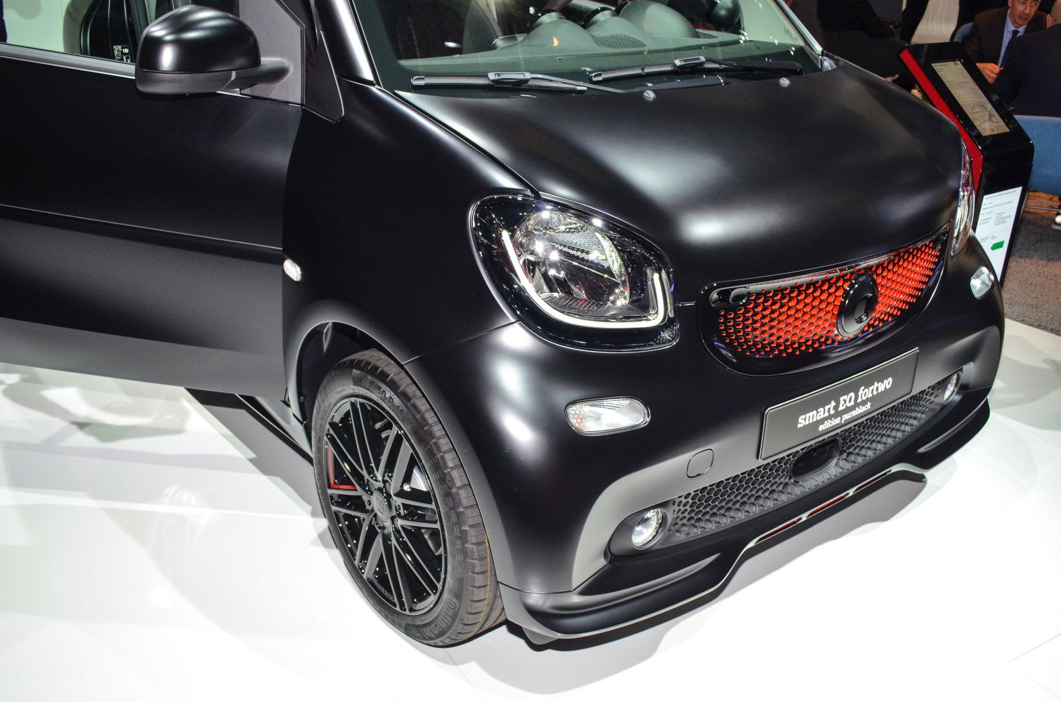 Close-up of front headlight and red-accented grille with black matte finish