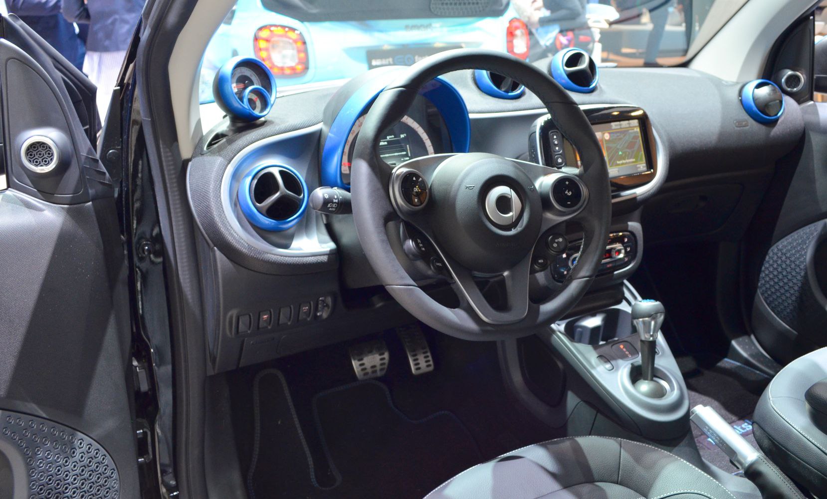 Steering wheel, blue-accented dashboard air vents, gear lever, and infotainment screen.