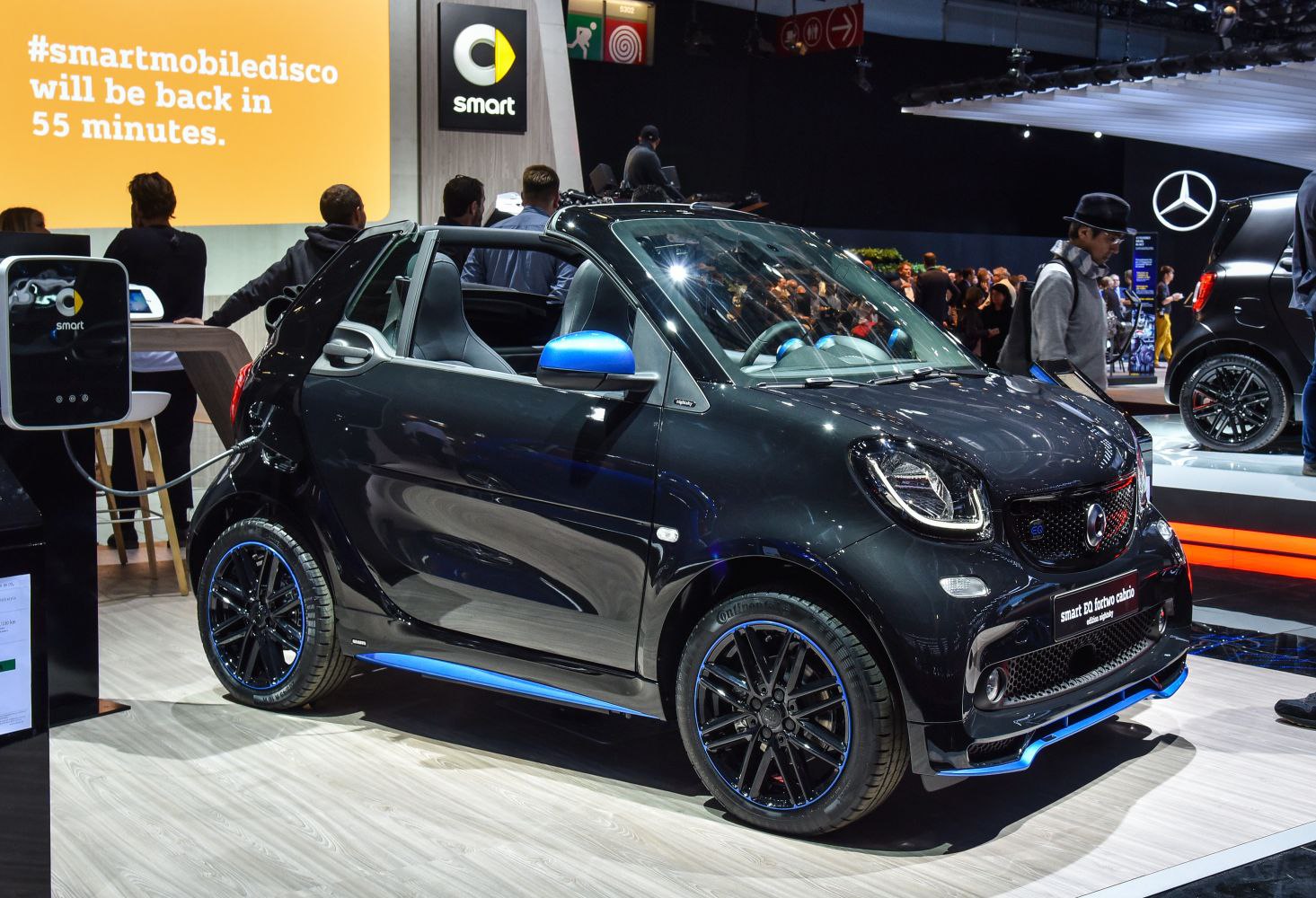 Black electric convertible with charging cable at auto show