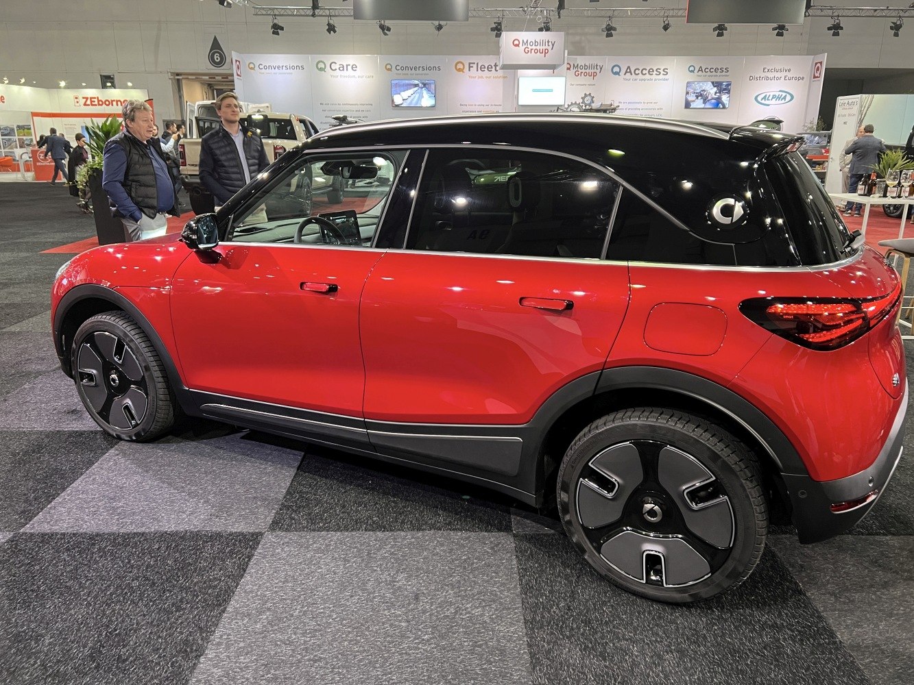 Red black compact electric SUV with unique futuristic wheel design.