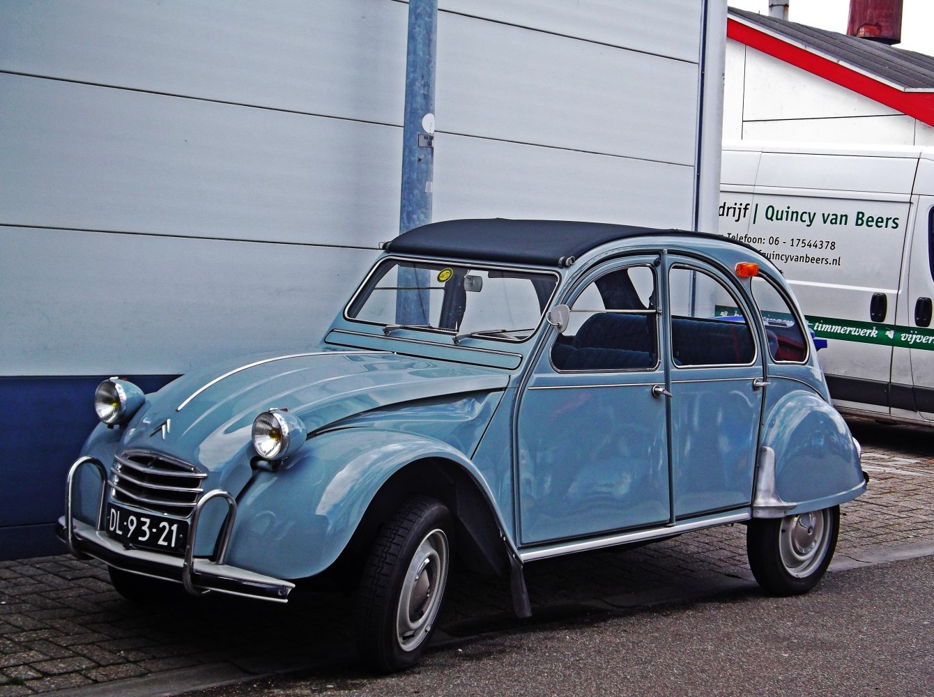 Blue classic compact car with convertible soft top and rounded headlights