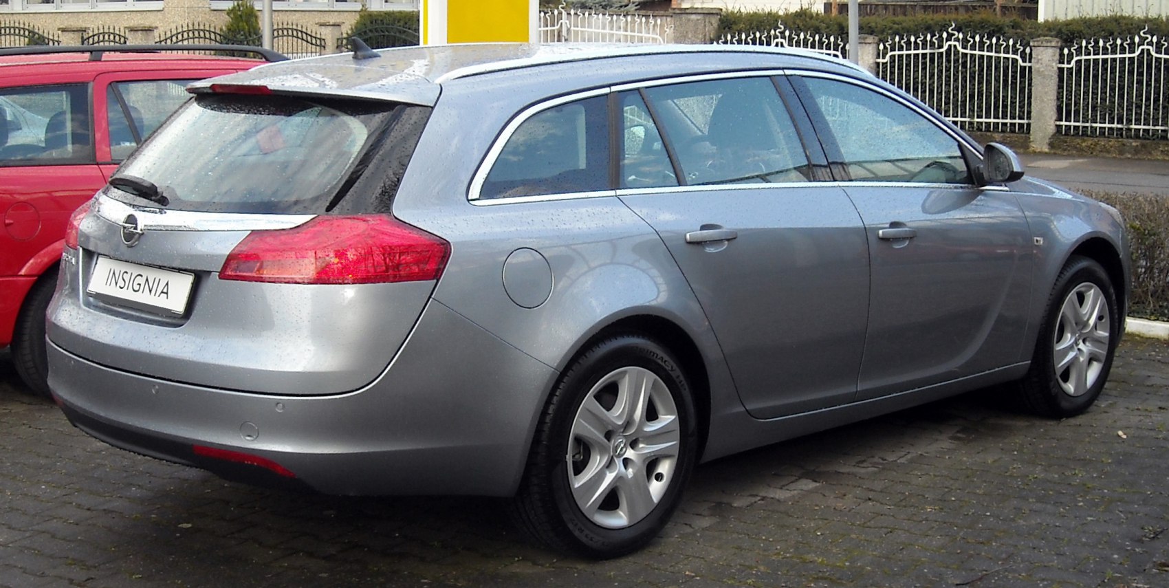 Rear and side view of silver estate car with roof rails and large taillights