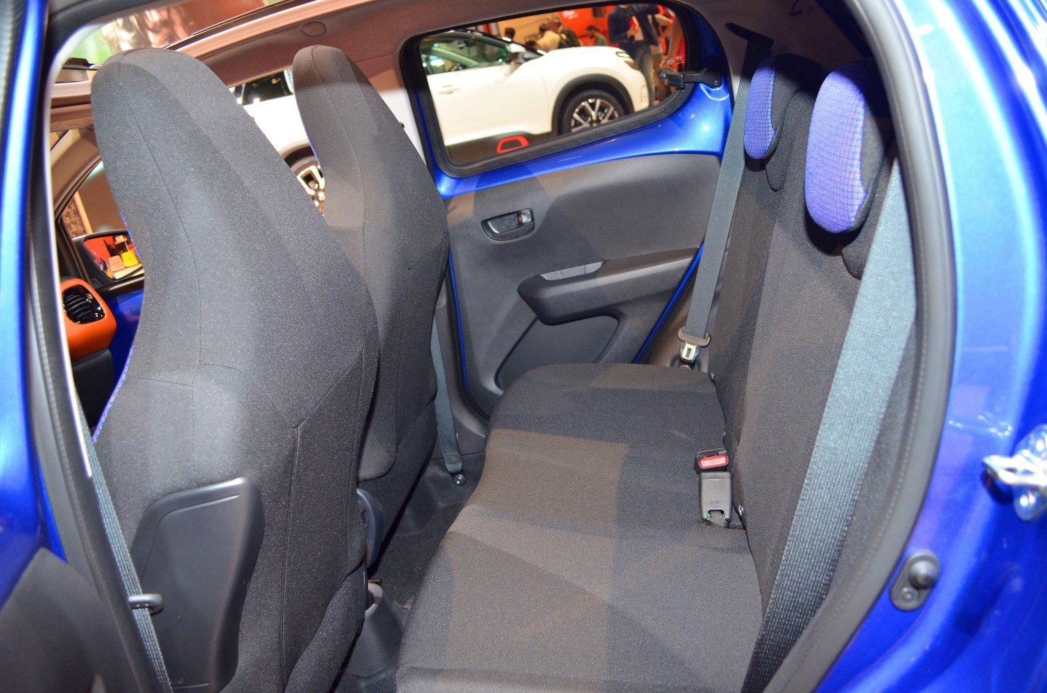 Compact rear passenger seating with fabric upholstery and headrests.