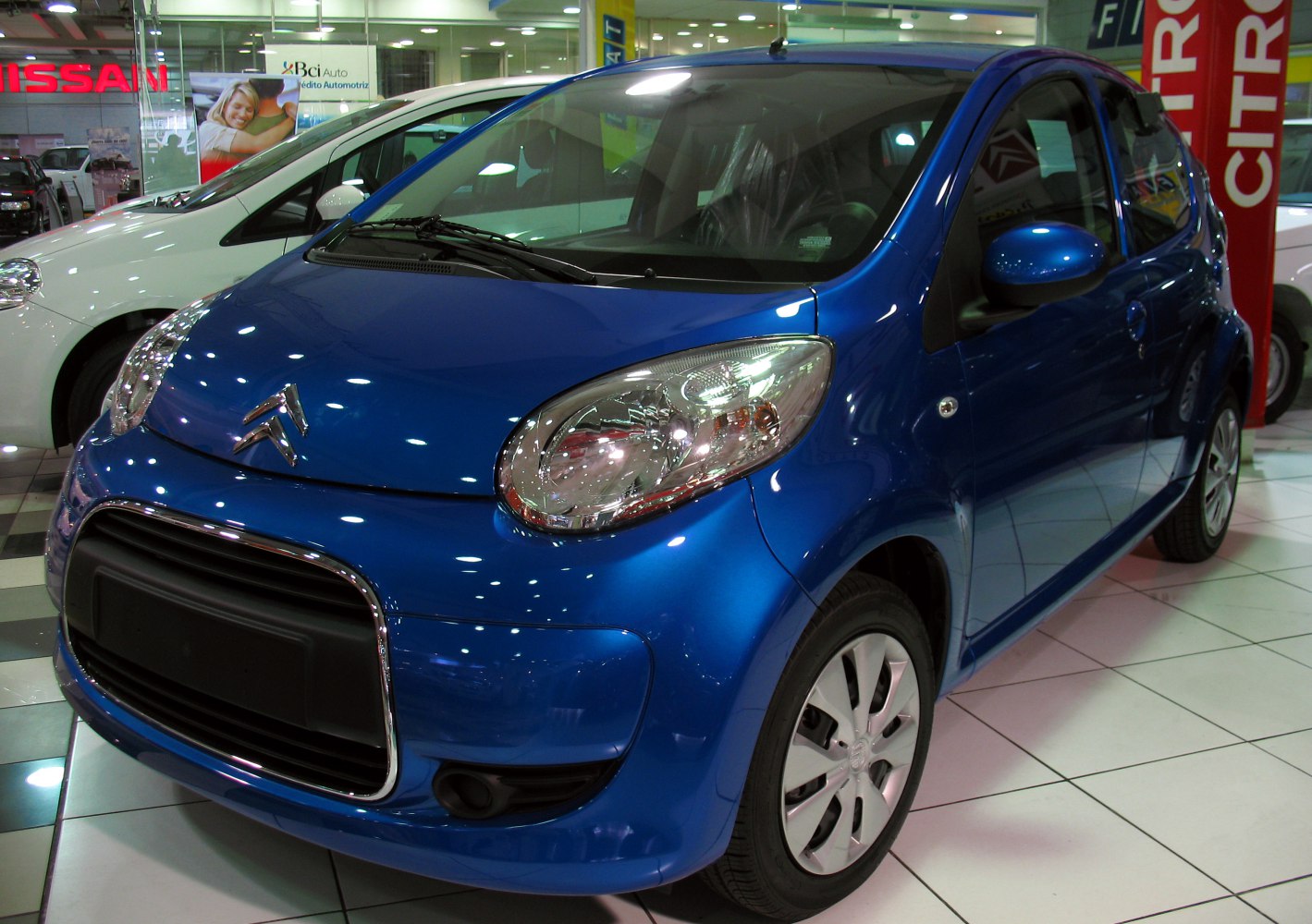 Front and side view of a blue compact 3-door hatchback with distinctive headlights and grille.