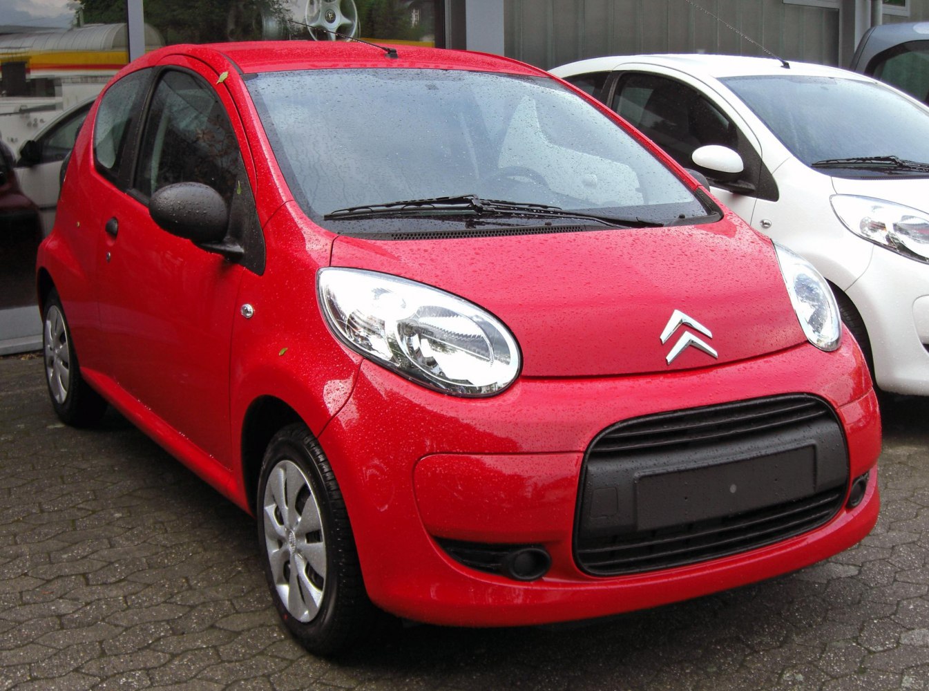 Red compact hatchback with large headlights and black grille