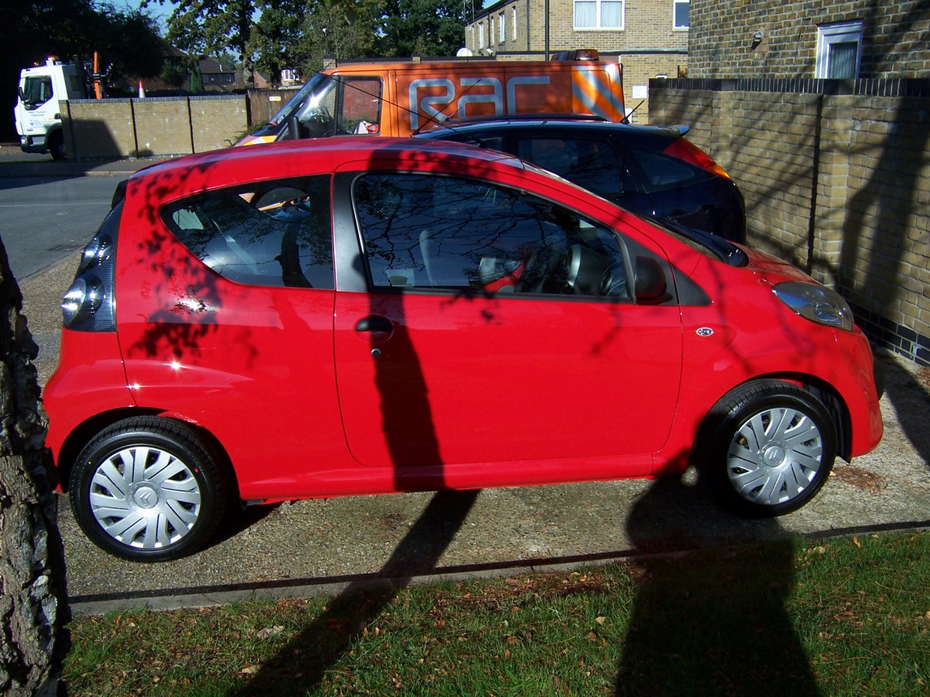 Compact red 3-door hatchback with distinctive rear lights and silver wheel covers