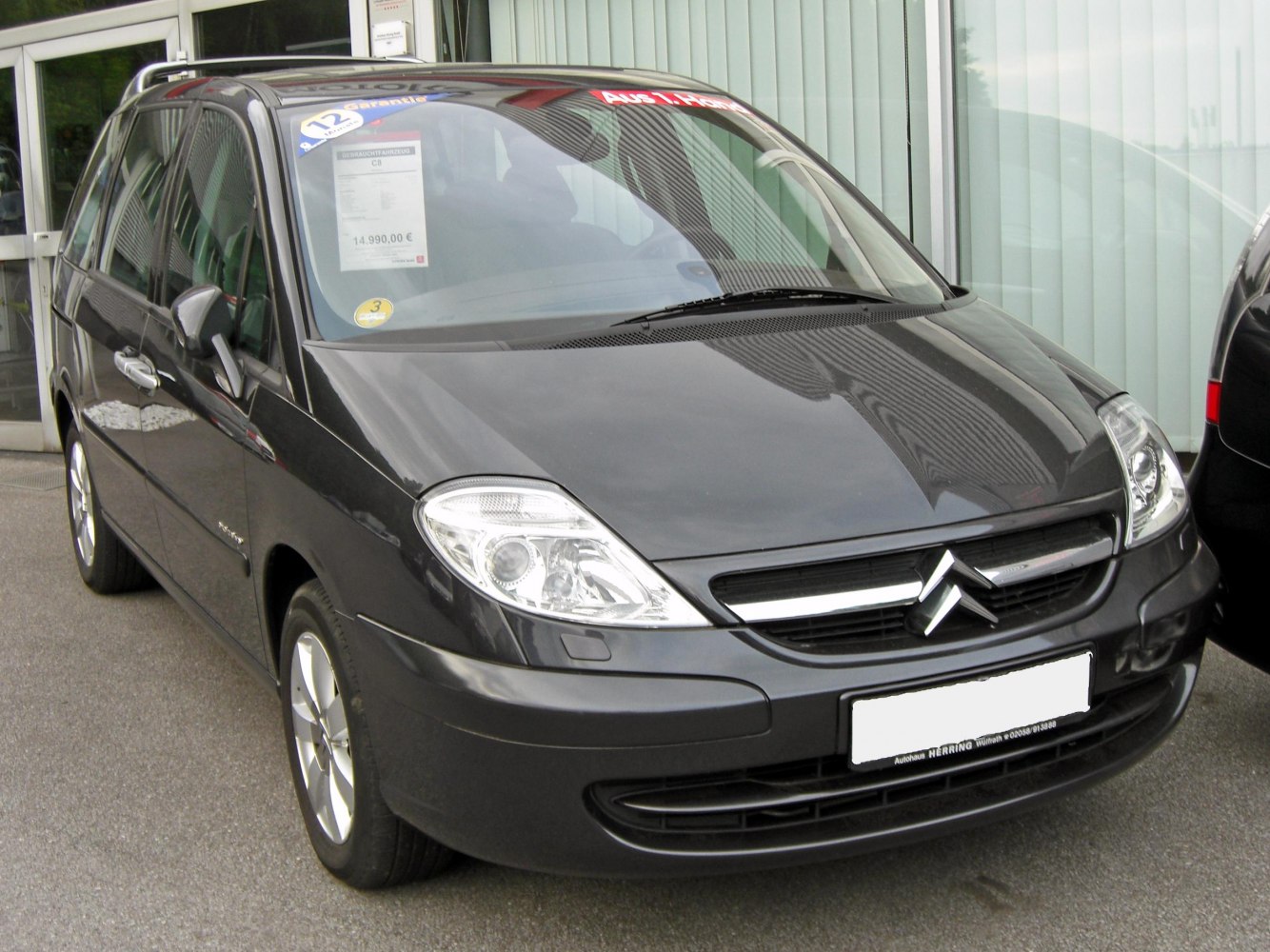 Front section with prominent headlights and grille of an MPV in black.