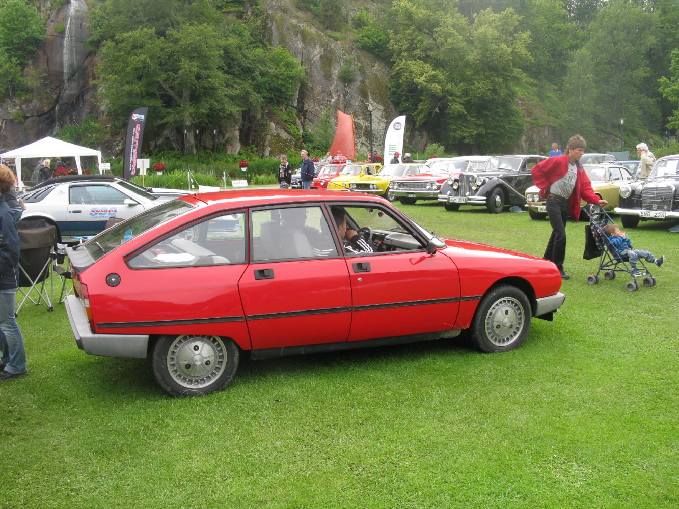 Red vintage 5-door hatchback parked on grass at car event