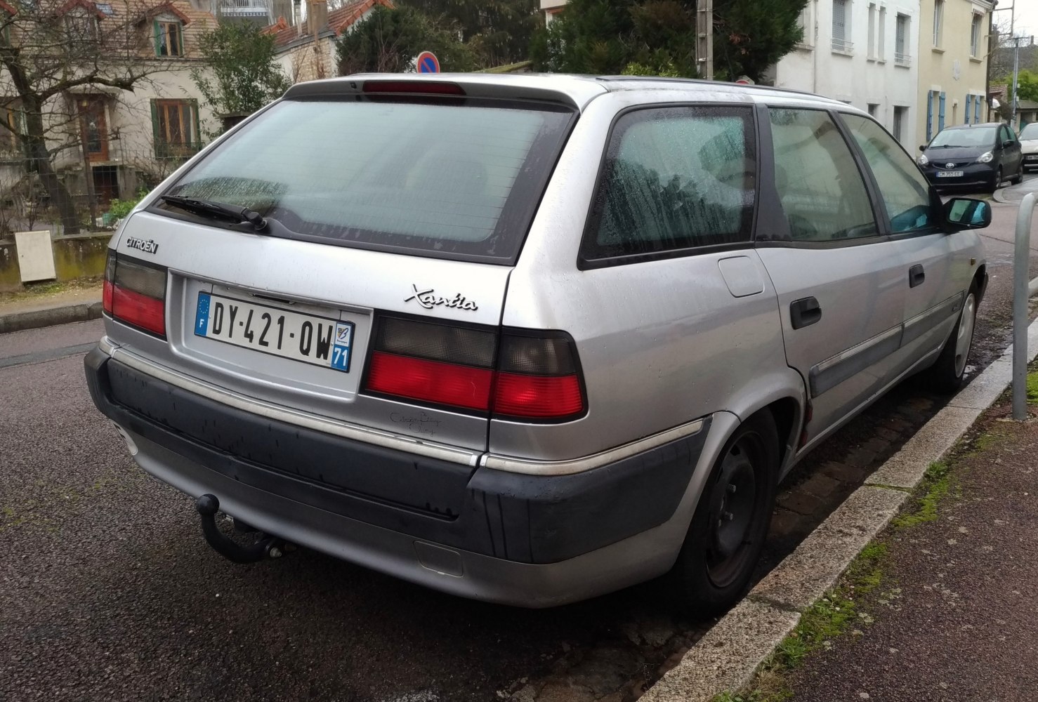 Rear side view of a silver station wagon with tail lights and rear window wiper