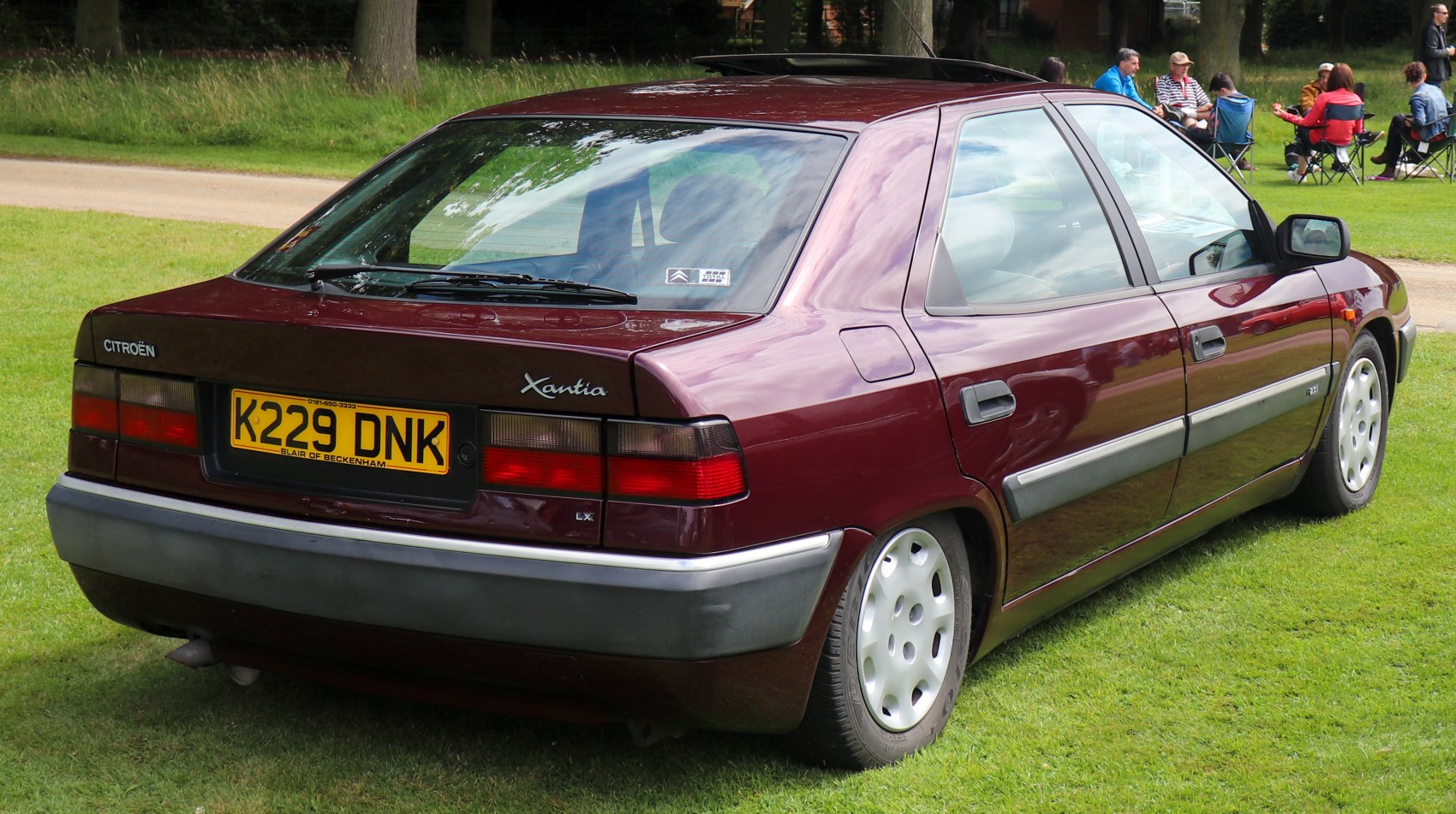 Rear and side profile of a burgundy 1993 hatchback with angular design and distinct tail lights.