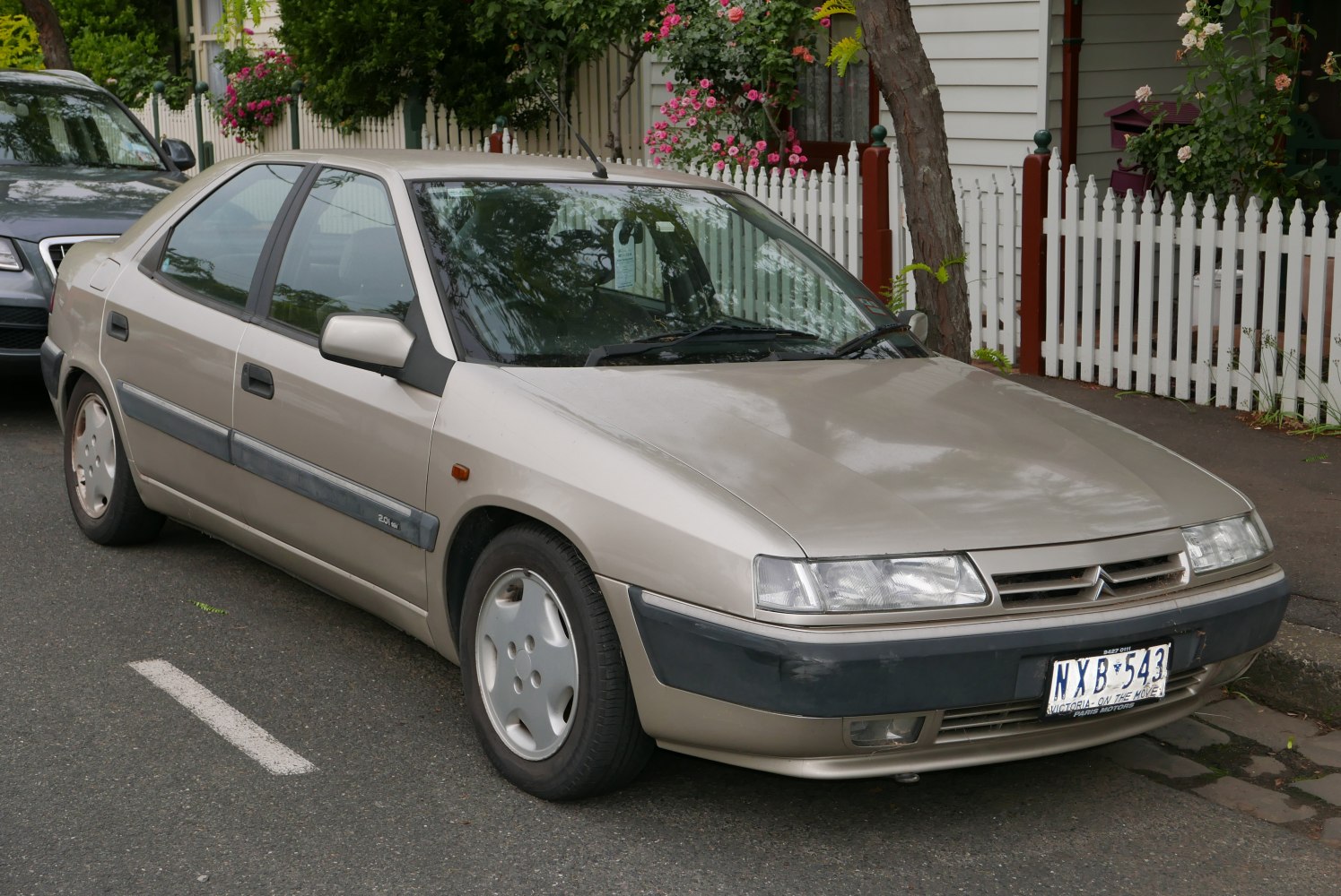 Front-side profile of a 1990s sedan with aerodynamic body and distinctive headlights