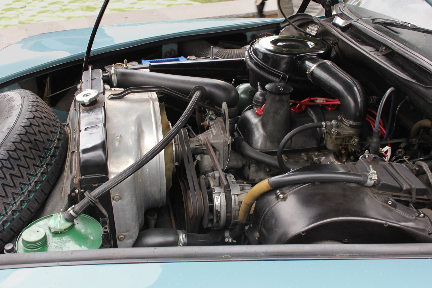 Classic car engine bay with spare tire and mechanical components