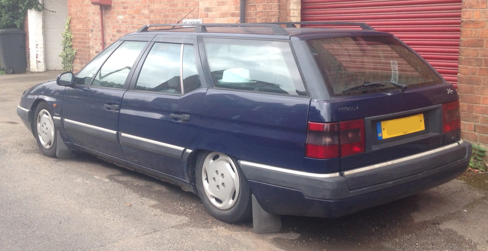 Side and rear view of a lowered station wagon with roof rails and mud flaps