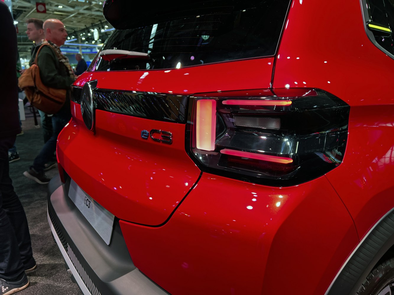 Close-up of modern rear LED tail light and emblem on red compact vehicle.