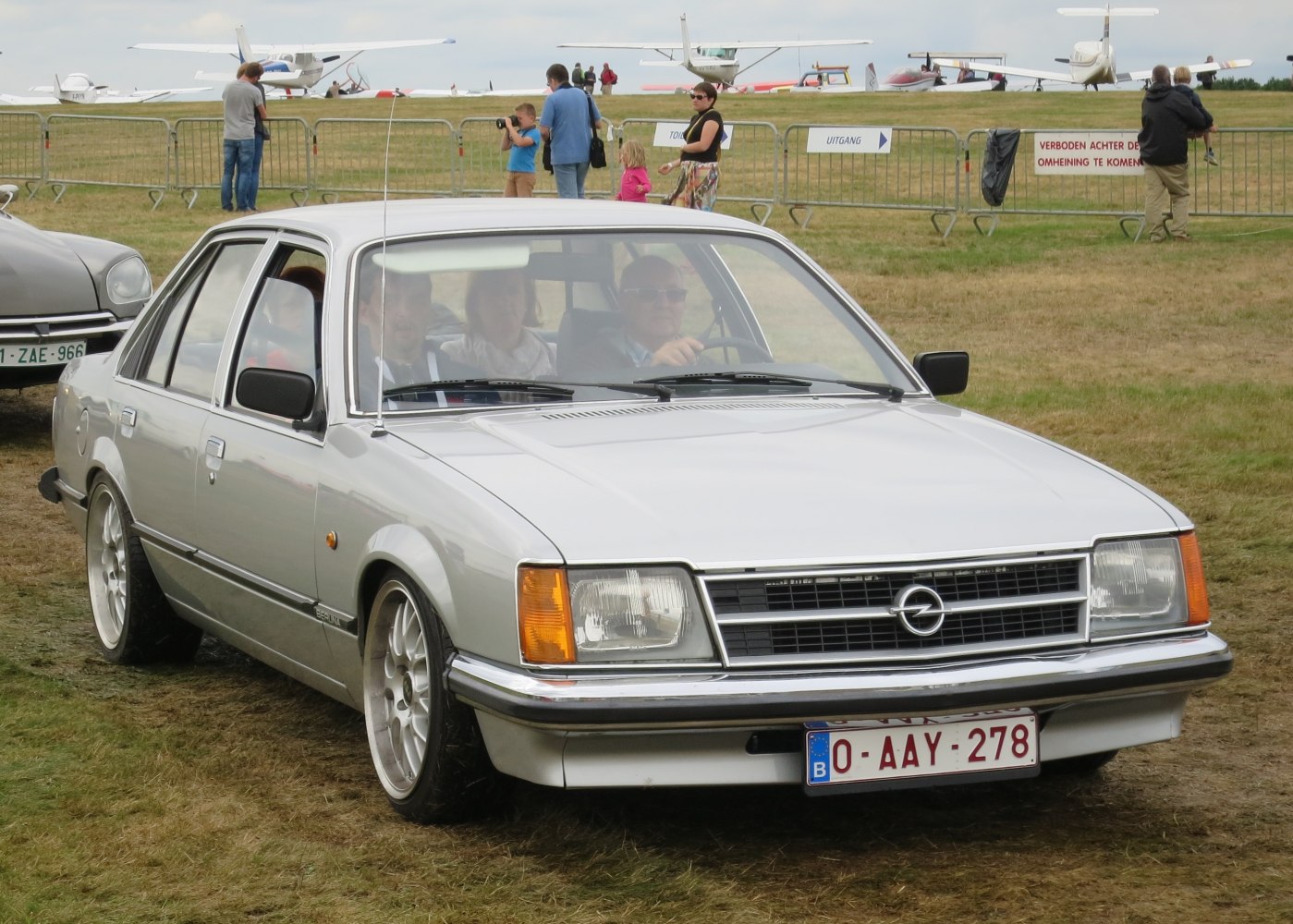 Silver sedan front corner with rectangular headlights and chrome grille