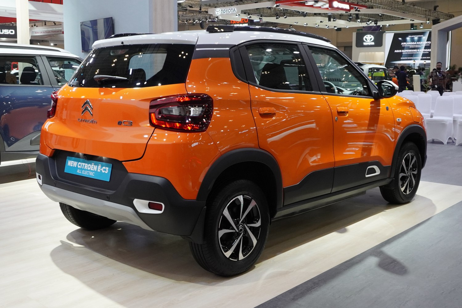 Rear-side view of two-tone orange and white compact electric SUV with modern taillights and alloy wheels
