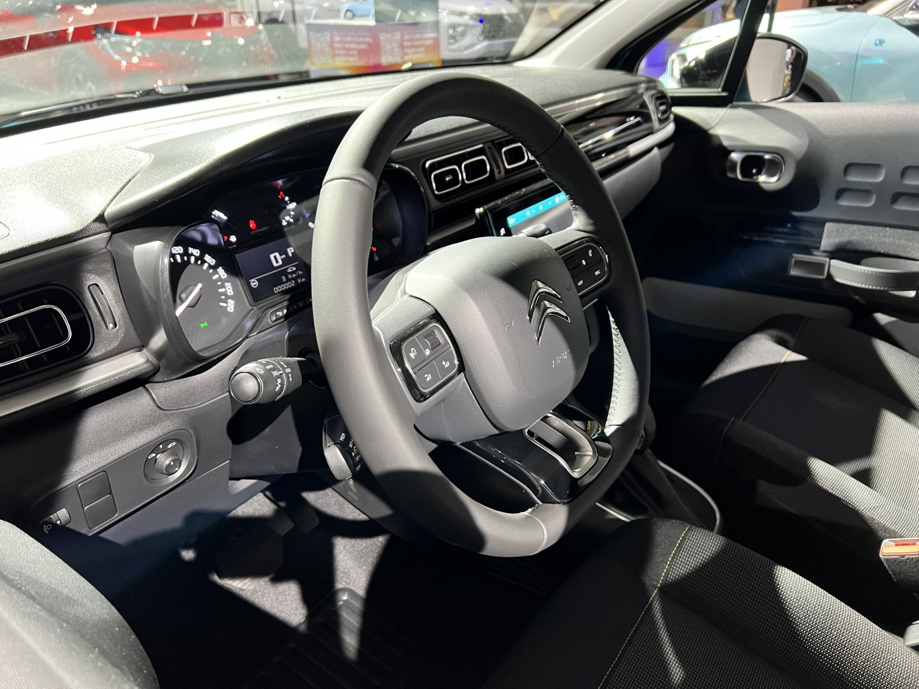 Steering wheel and dashboard with instrument cluster and central touchscreen.