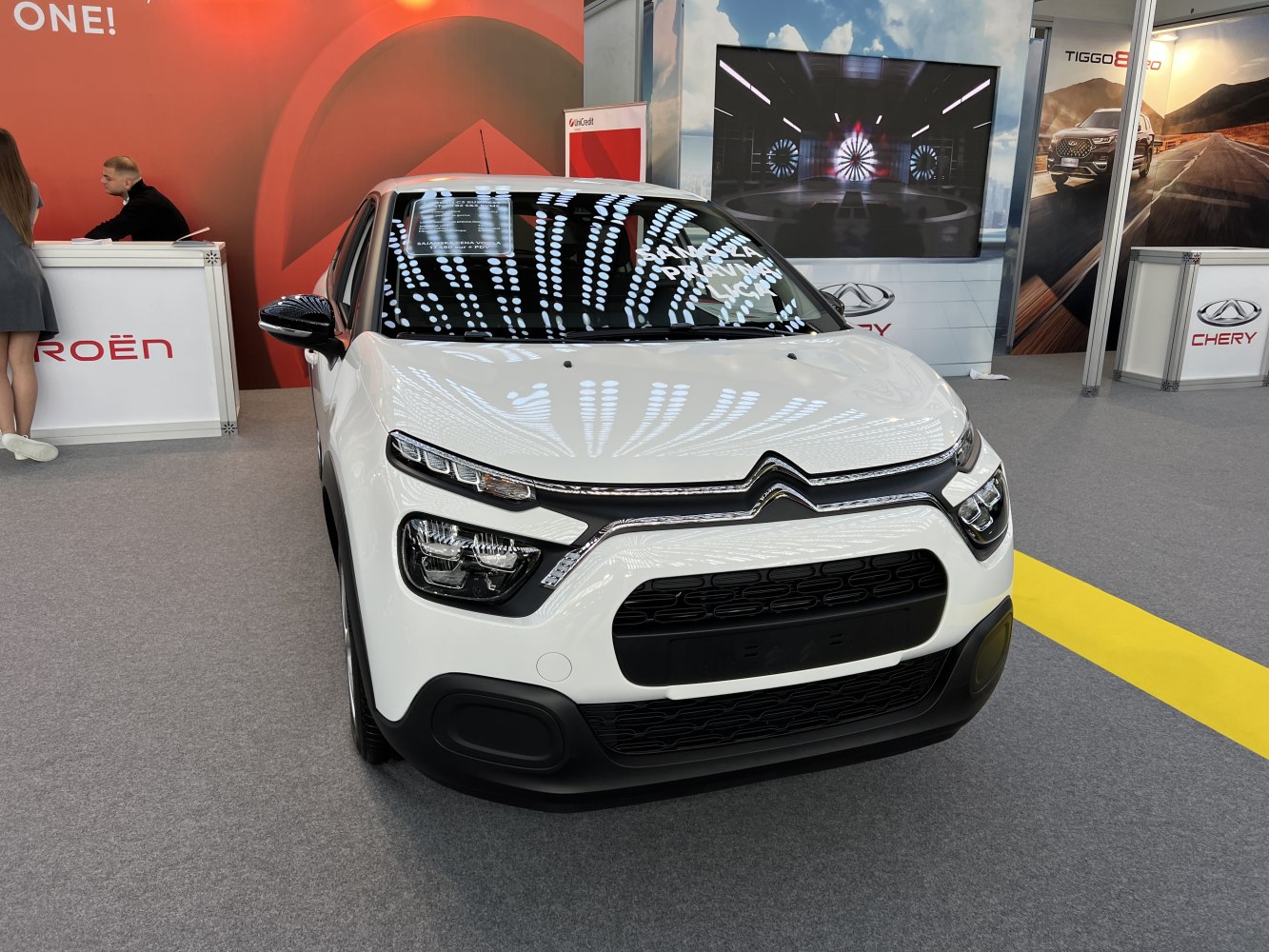 Front view of white subcompact hatchback with split headlights and black grille