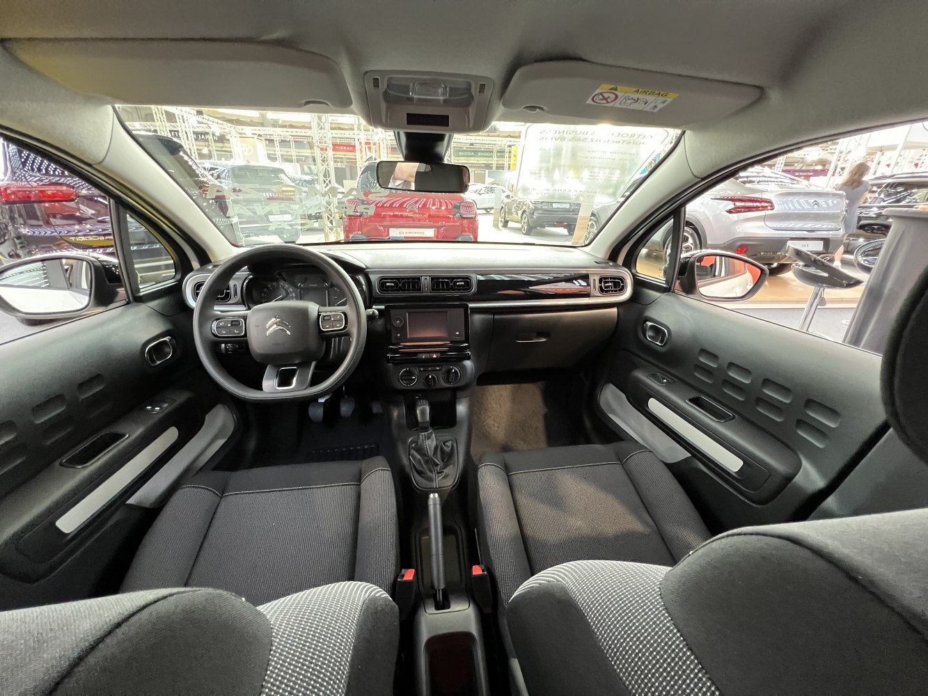 Compact interior with dashboard, steering wheel, touchscreen, and fabric seats