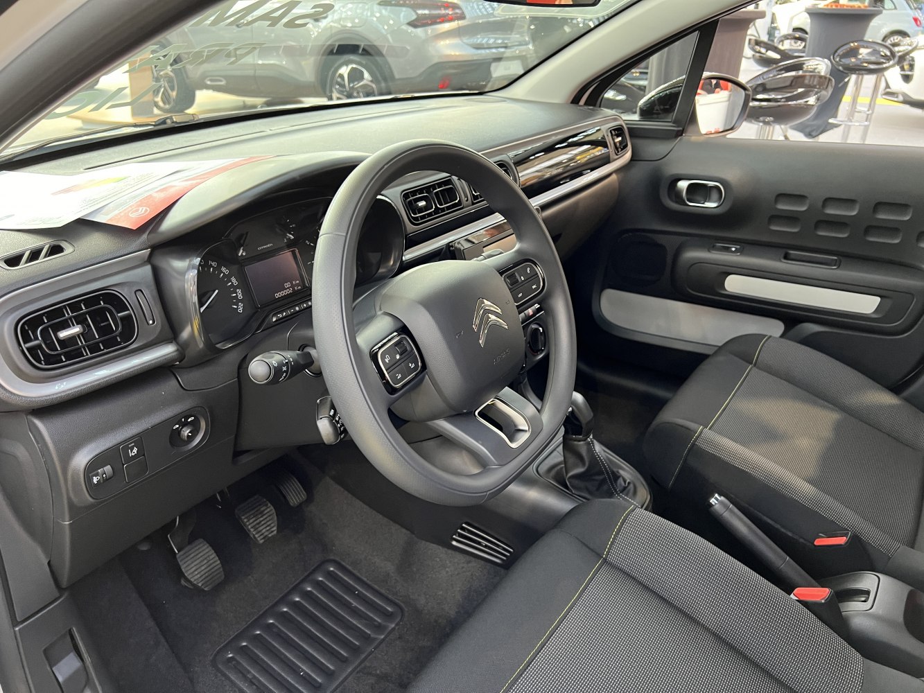 Steering wheel, dashboard with vents, and seating inside vehicle
