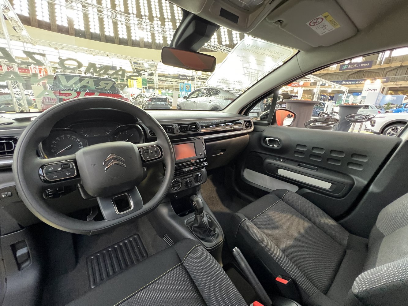 Dashboard, steering wheel, and front seats of a compact car interior.