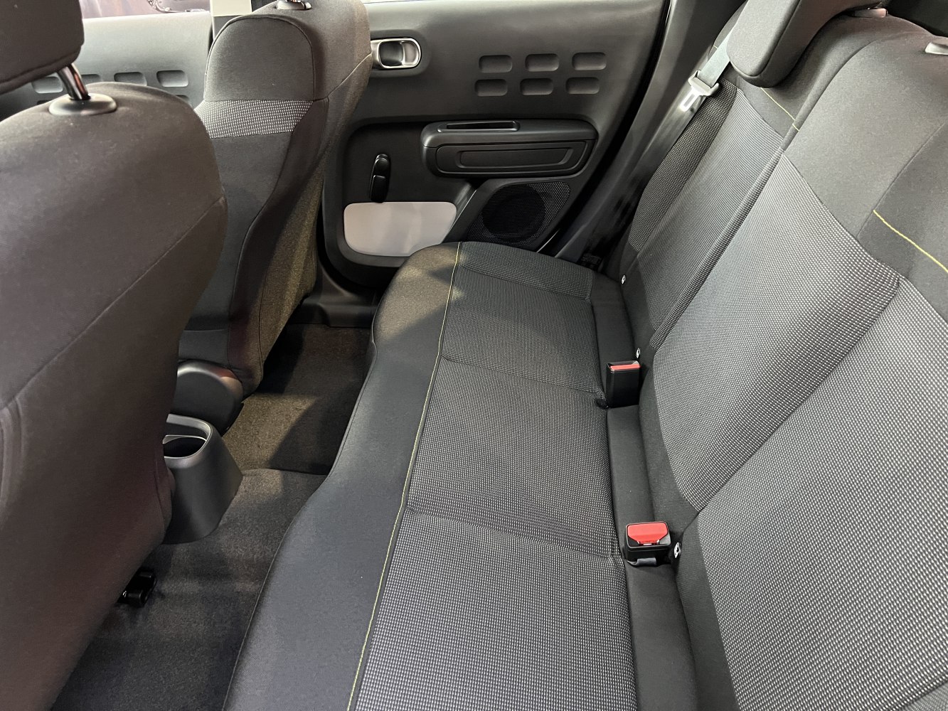 Rear fabric seats and door panel with upholstery and seat belts.