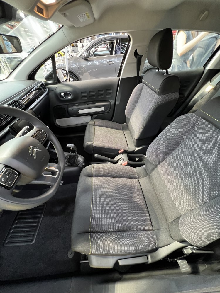 Front fabric seats and manual gearshift in car interior with dashboard and door details