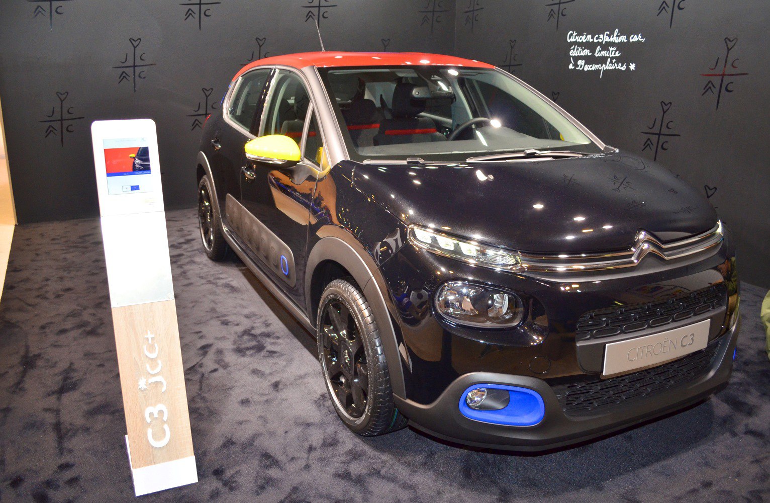 Compact hatchback with black body, red roof, yellow mirrors, and blue trim