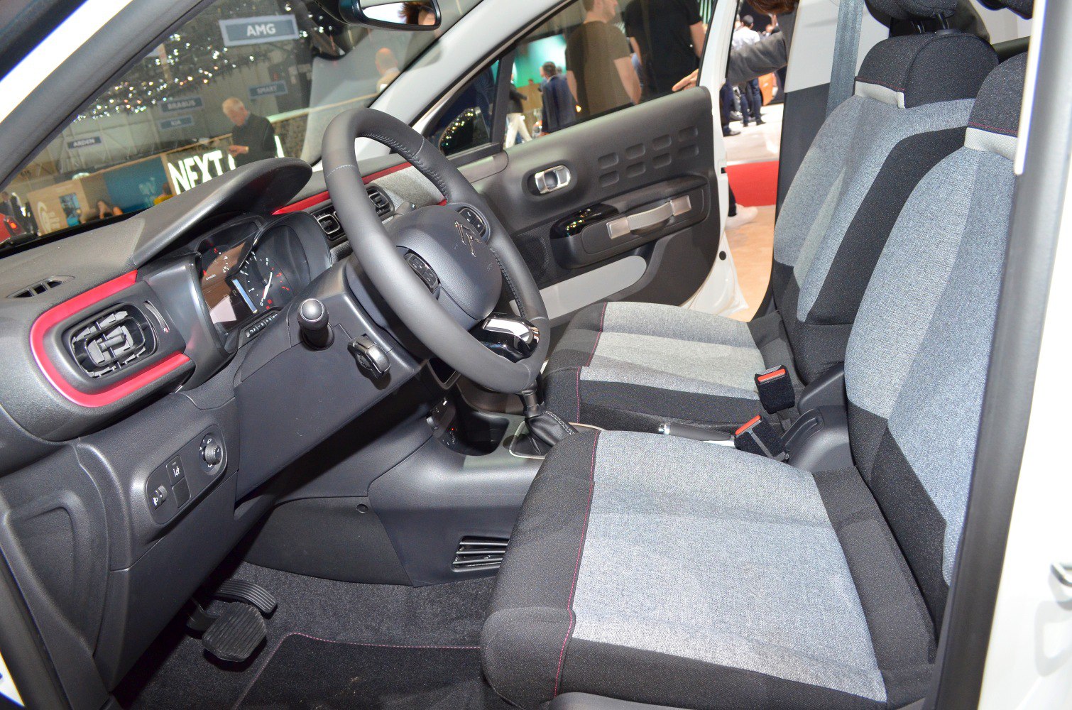 Dashboard, steering wheel, and fabric front seats of a compact car interior