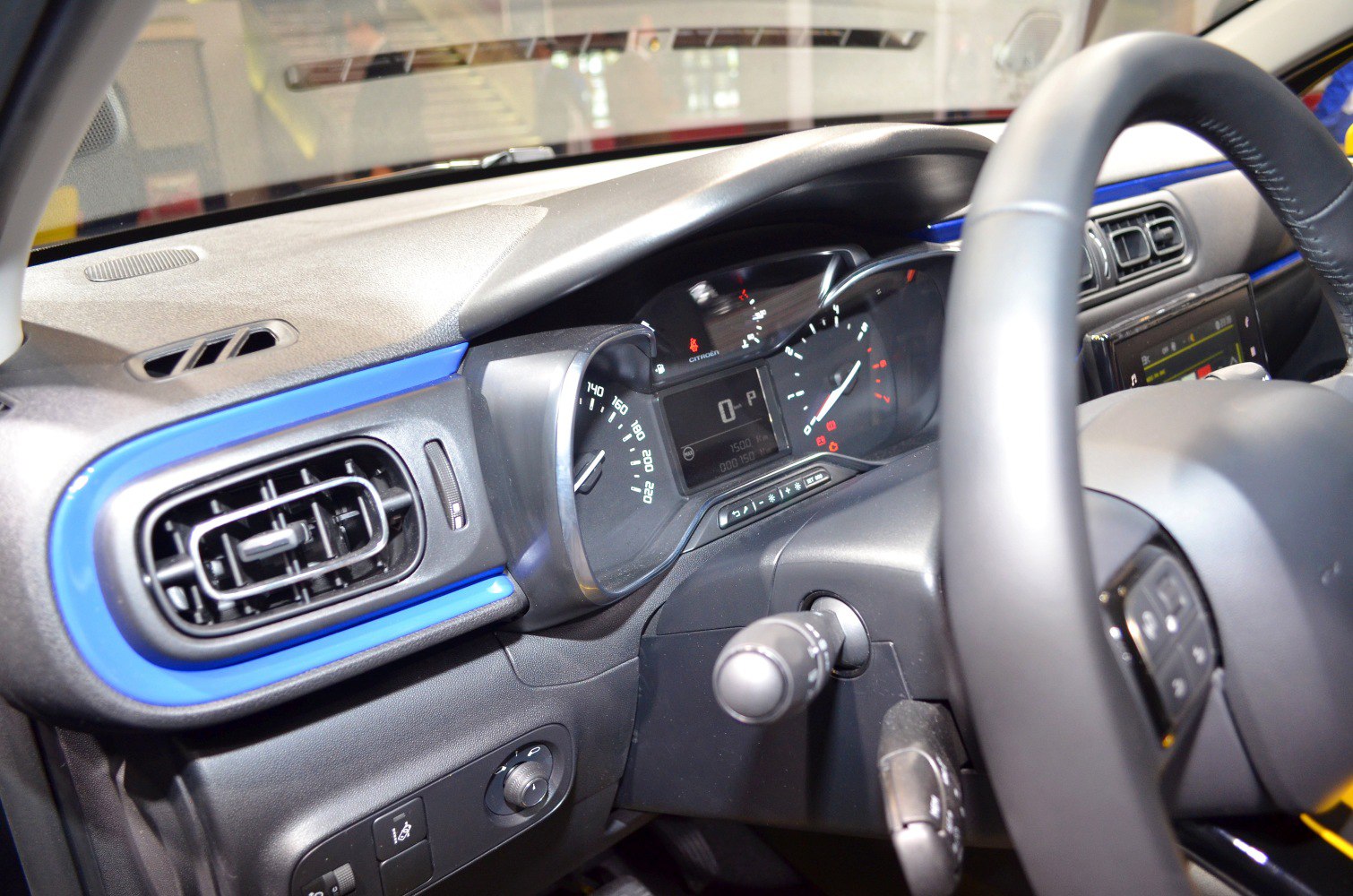 Dashboard and instrument cluster with blue trim, air vent, and steering wheel controls