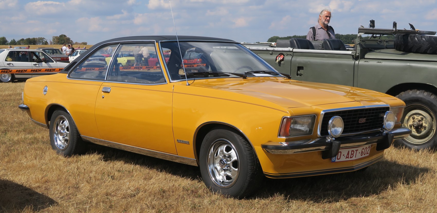 Yellow two-door coupe with black vinyl roof and chrome wheels