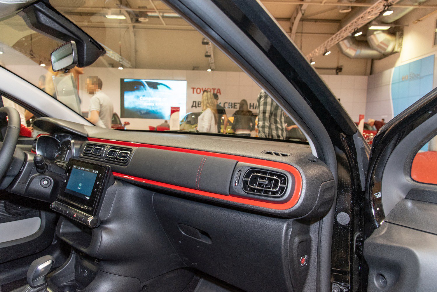 Interior dashboard with red trim, touchscreen, and air vents