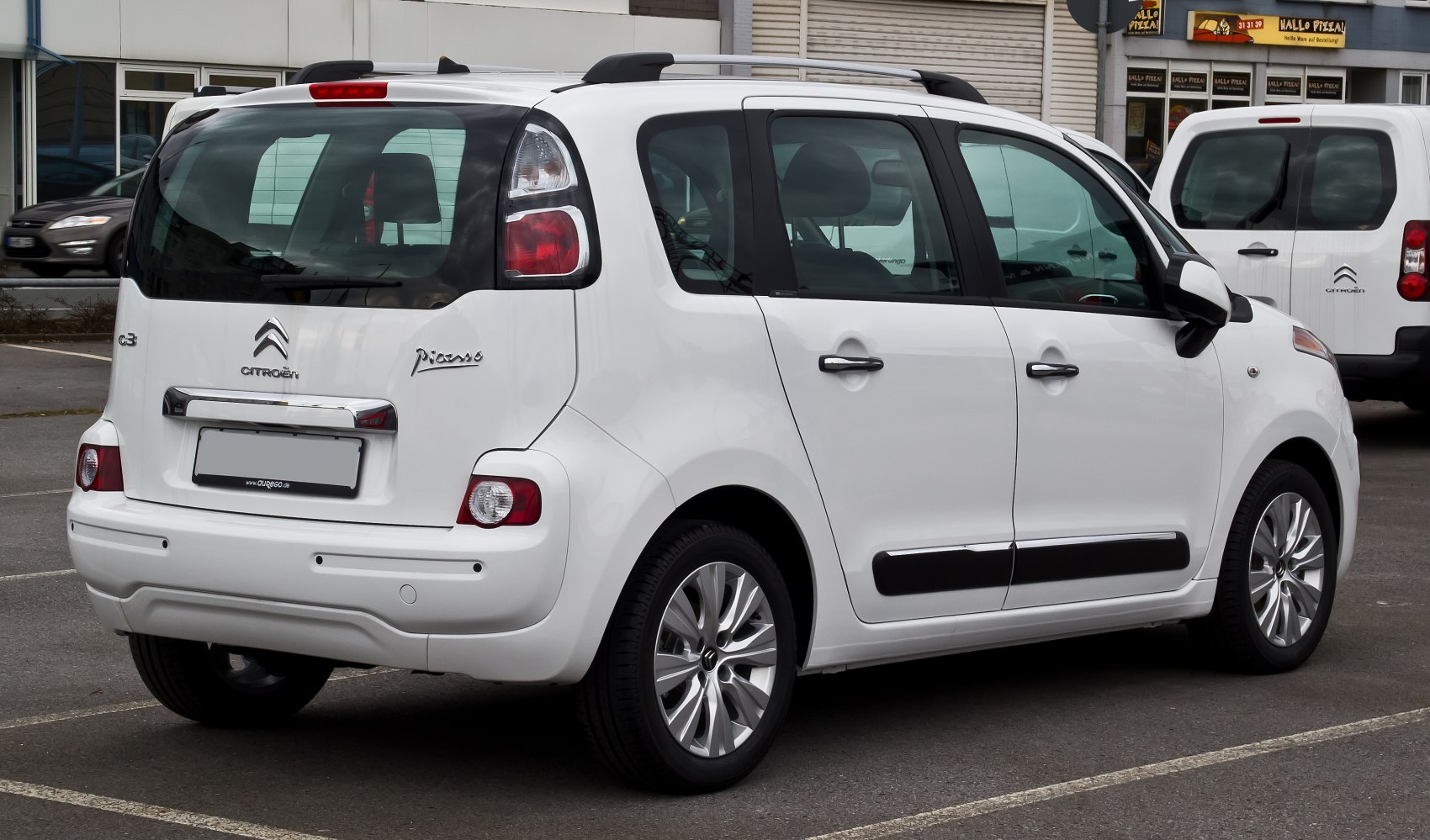 Rear view of a white compact MPV with unique tail lights and roof rails