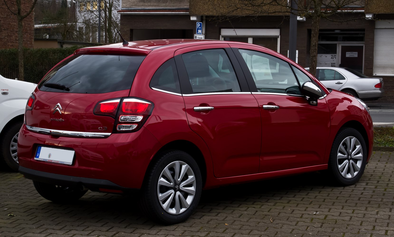 Rear side view of red hatchback with distinct taillights and alloy wheels