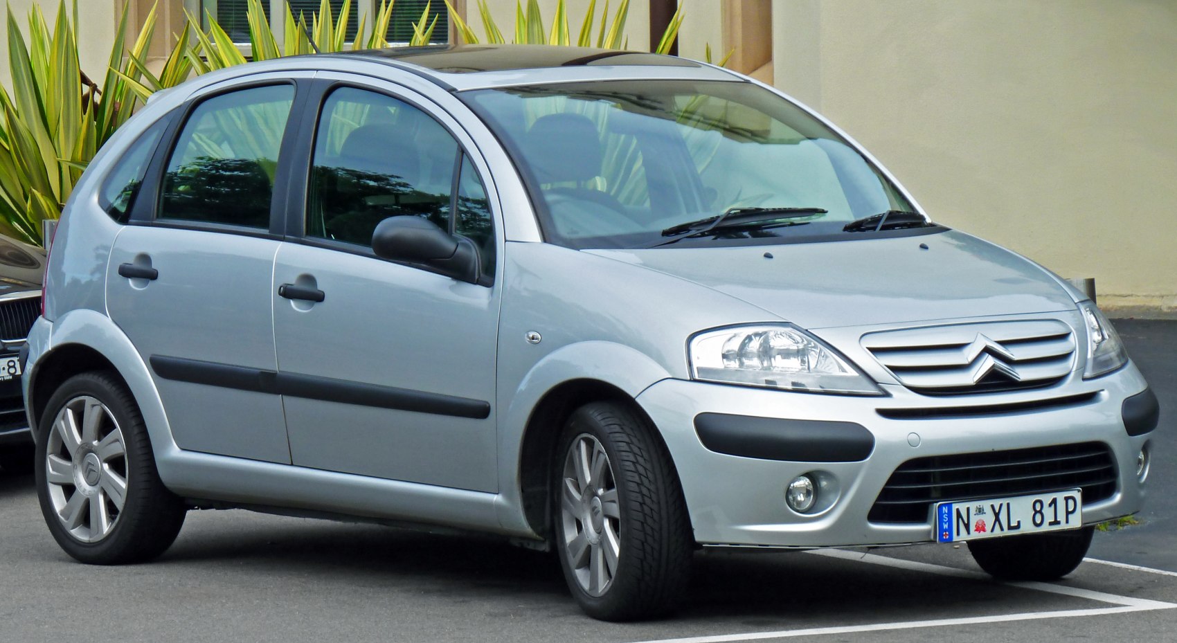 Silver compact hatchback with panoramic sunroof from front-side angle