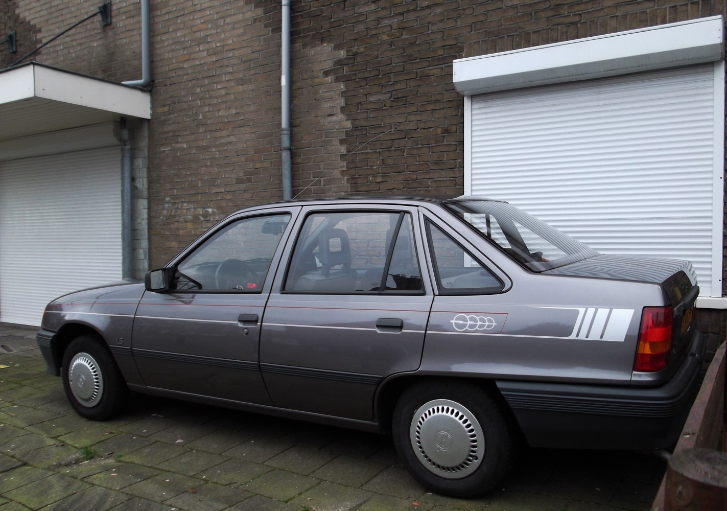 Side profile of 1980s four-door hatchback with distinctive decals and hubcaps