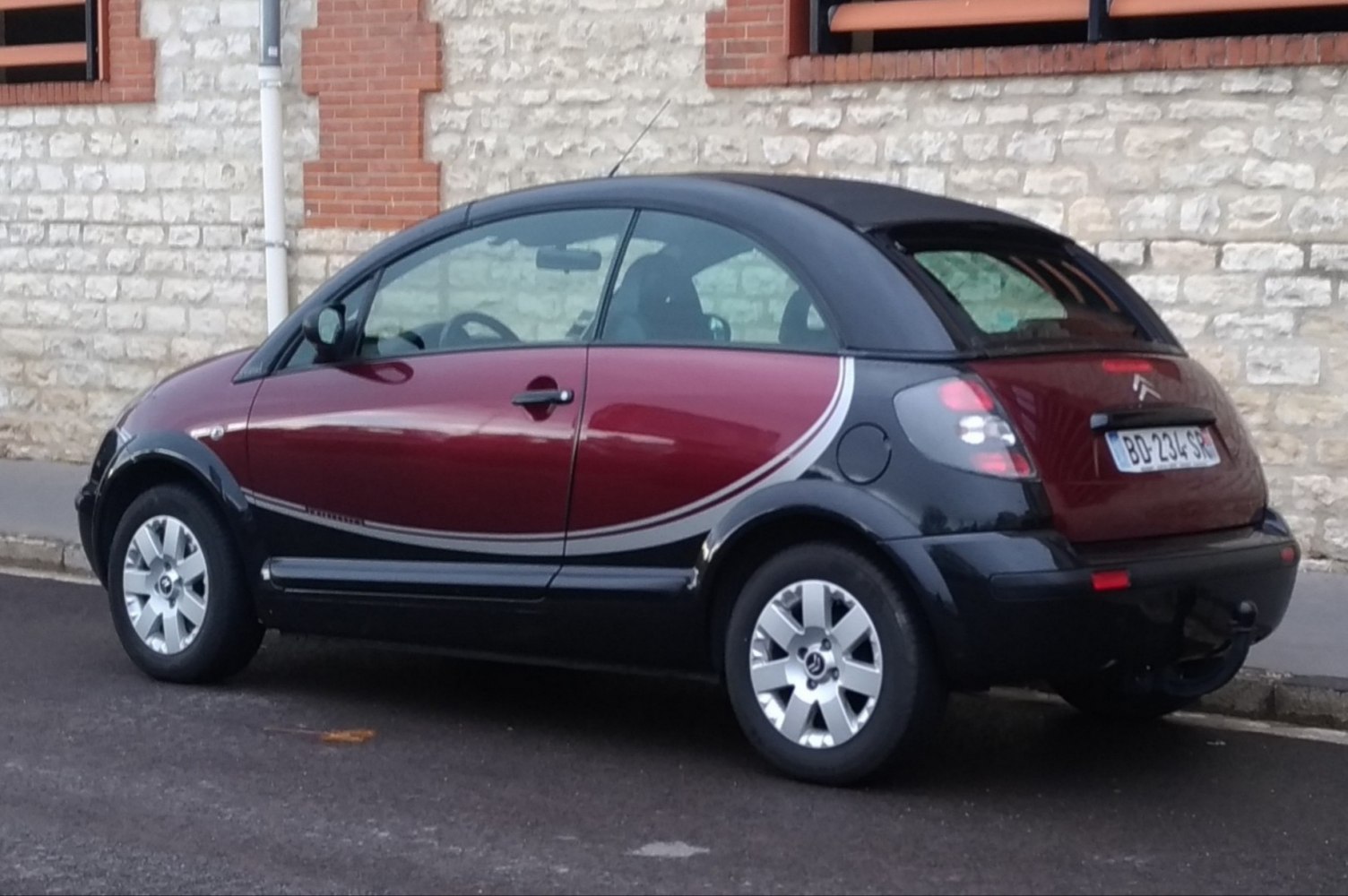 Side view of compact convertible with two-tone body and black soft top roof