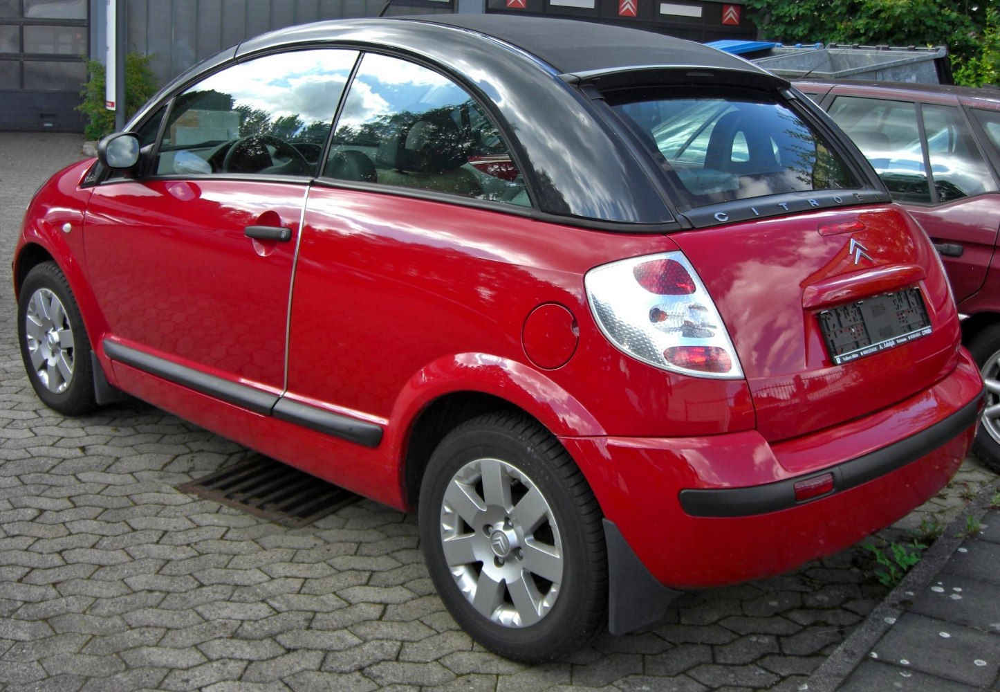 Red compact hatchback rear with black roof and alloy wheels.