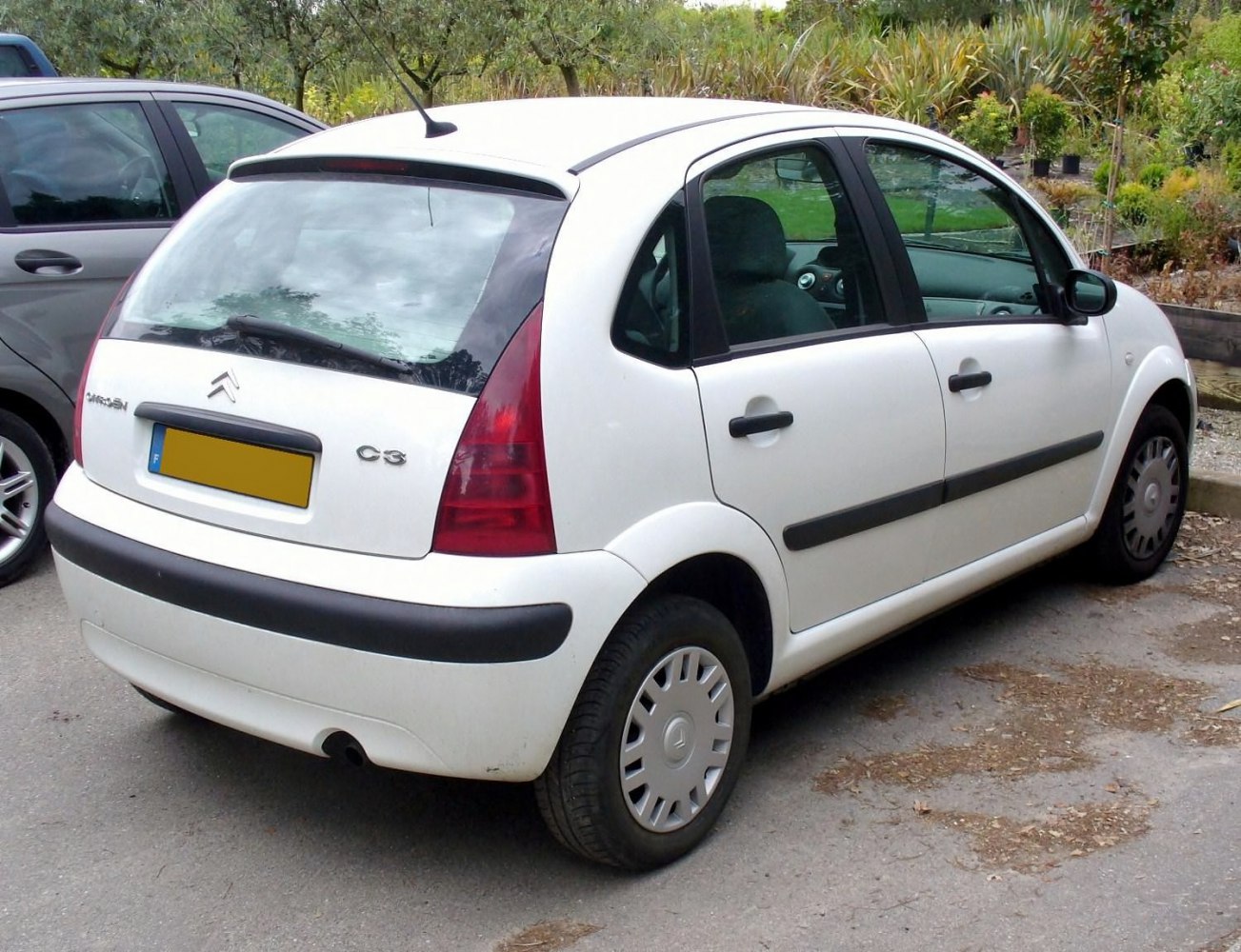 Rear side view of white hatchback with taillights and black side moldings