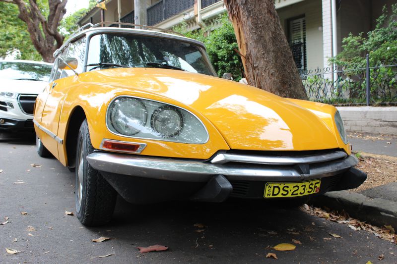 Close-up of vintage yellow car front with distinct headlights and bumper.