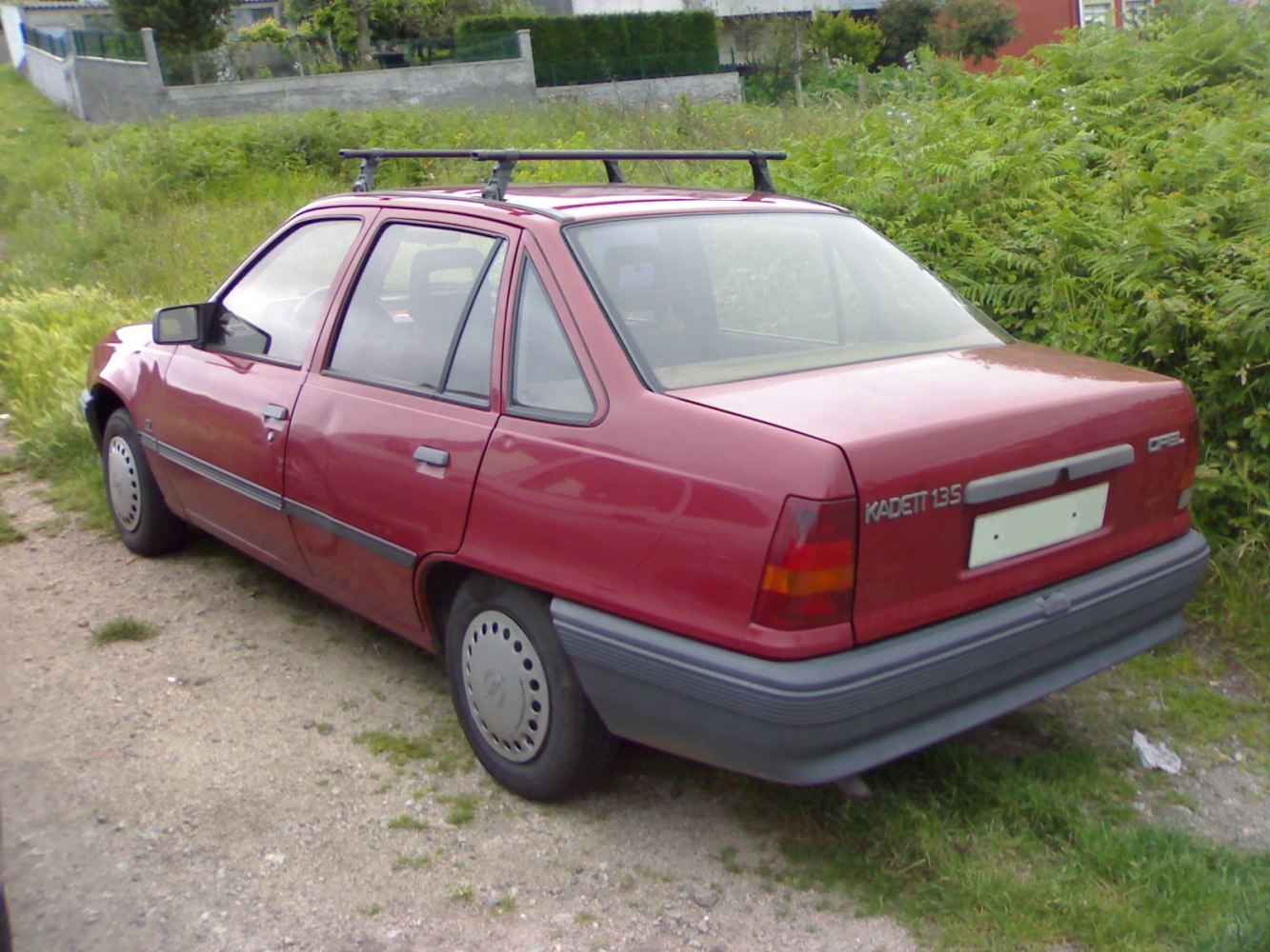 Red sedan with roof rack and rear side view