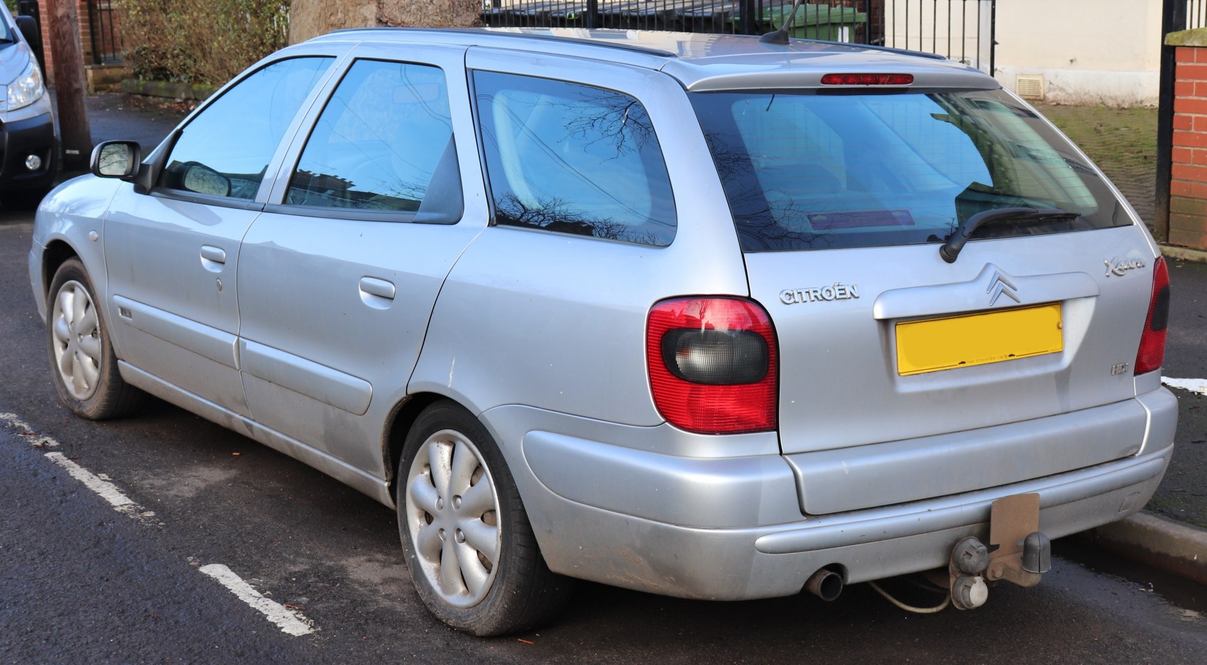 Rear-side profile of silver station wagon with alloy wheels and towing hitch