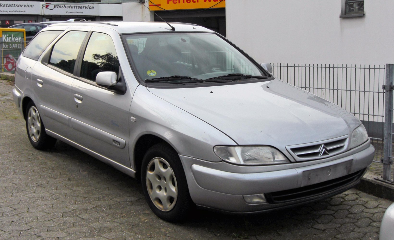 Silver wagon with smooth contour, headlight, side mirror, and front grille.