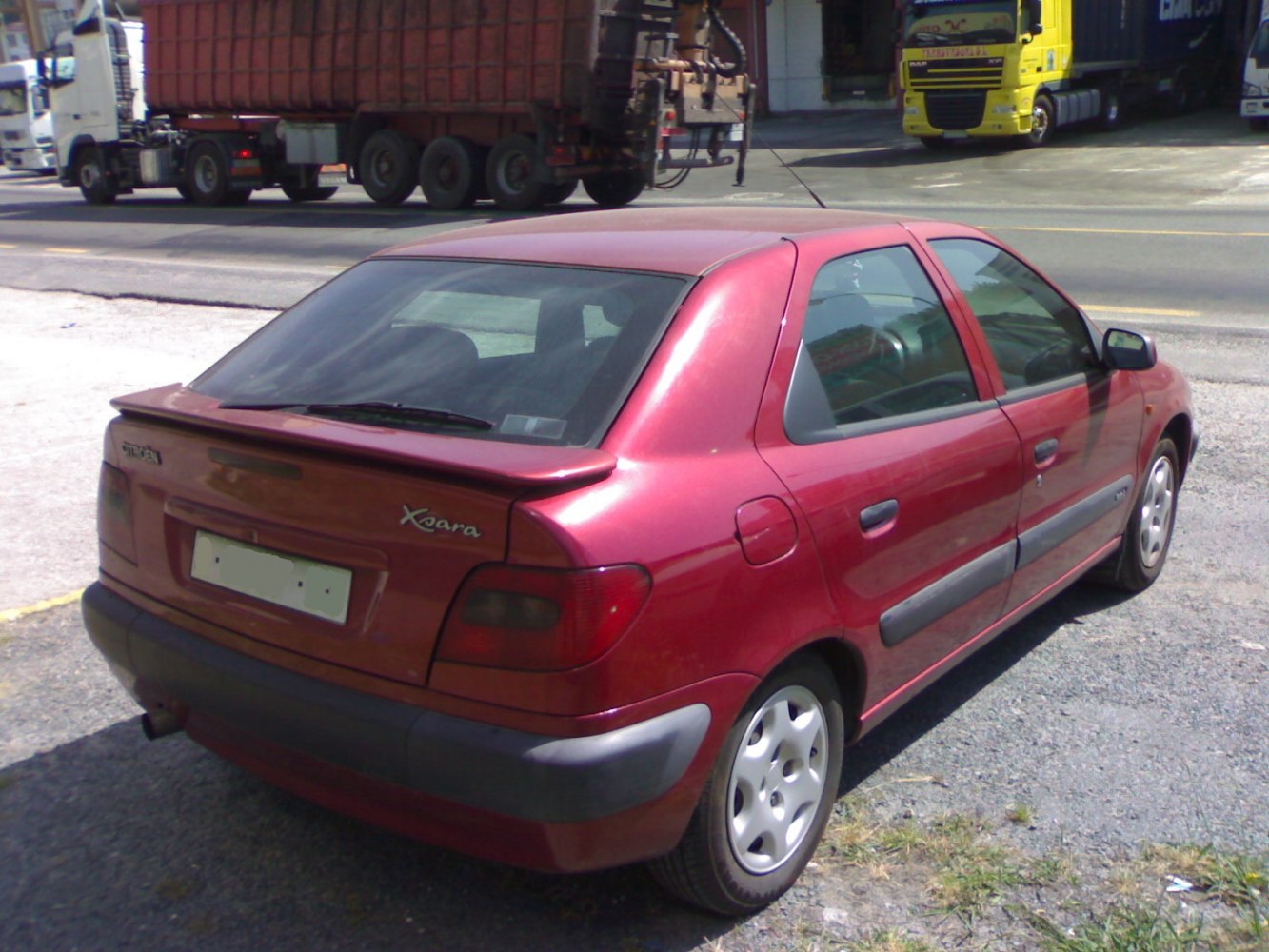 Rear side view of red hatchback with black bumper and distinctive taillights.