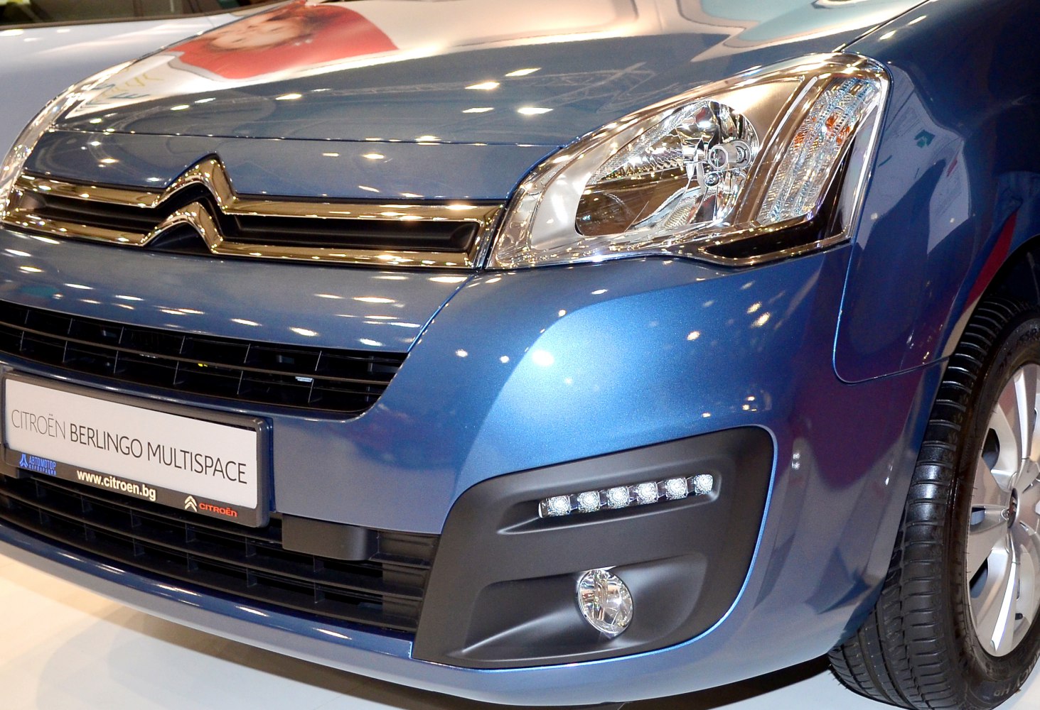 Close-up of front grille, headlight, daytime running lights, and fog light on a blue vehicle.